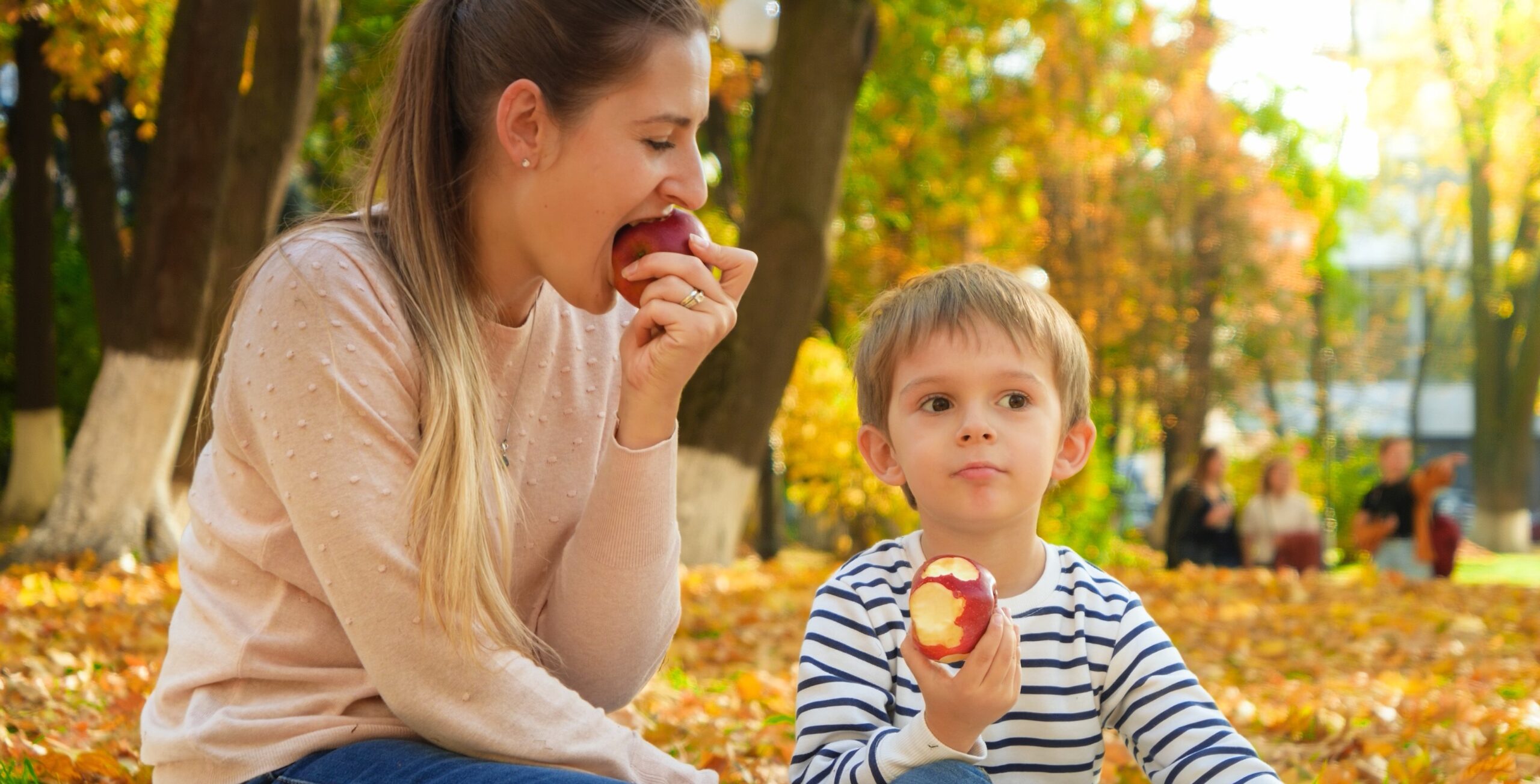 A mother and son enjoy erating apples in the fall.